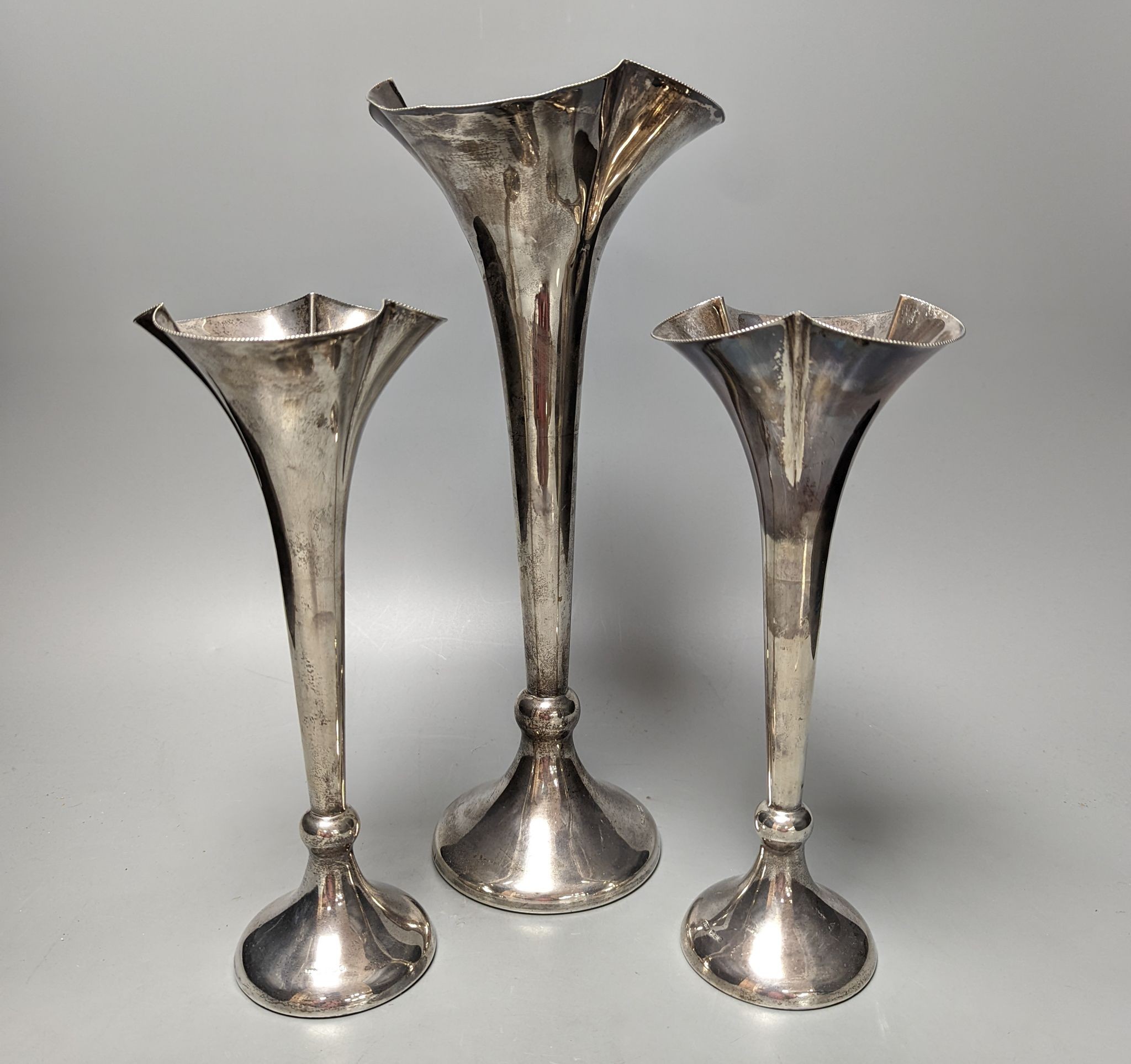 A large George V silver mounted trumpet vase, 34cm and a pair of smaller silver mounted vases.